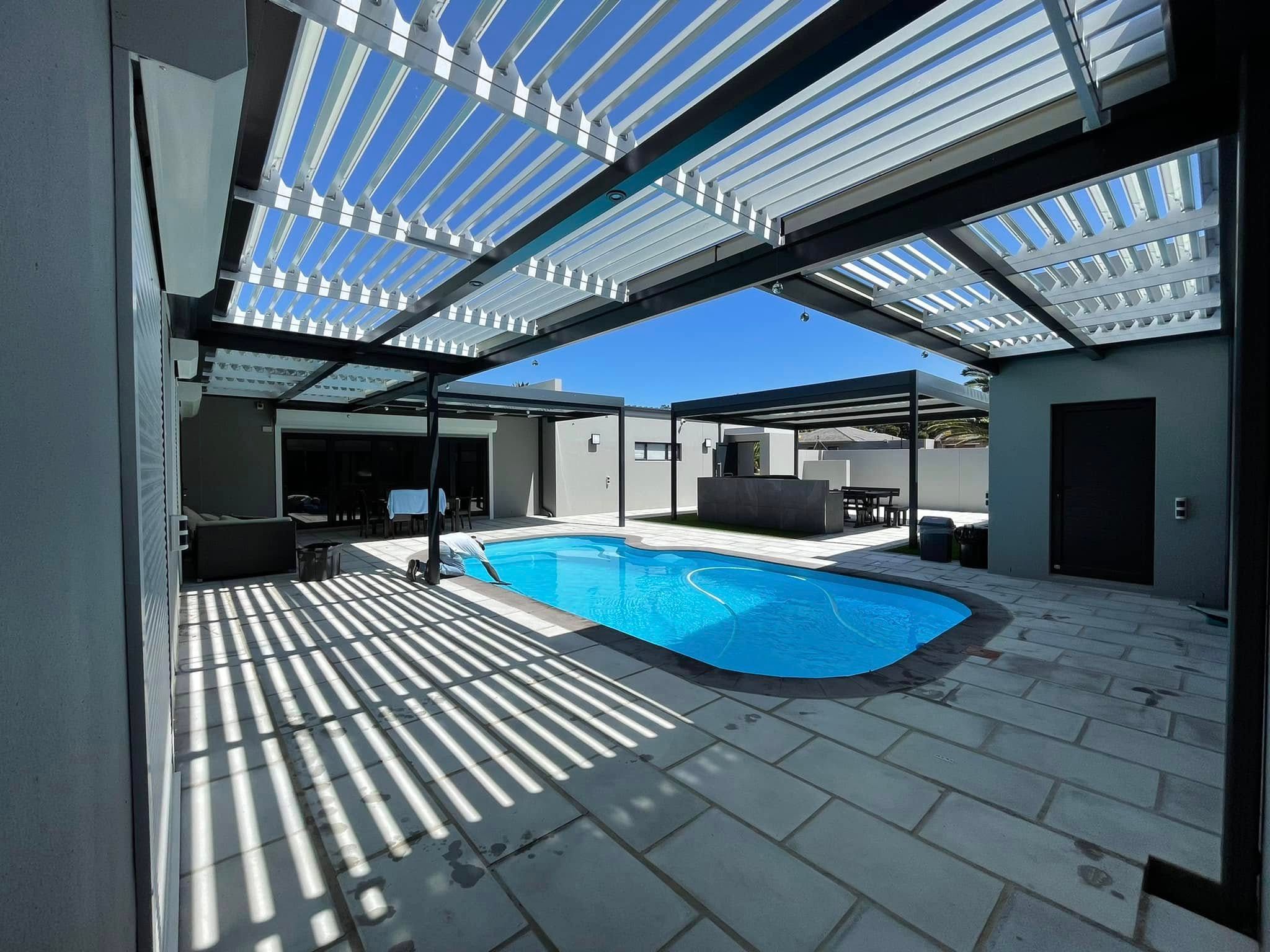 Open white louvres casting striped shade over a pool deck